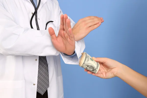 Male Doctor receiving money from patient, on blue background — Stock Photo, Image