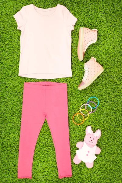 Yeşil halı üzerinde küçük kız için güzel elbiseler