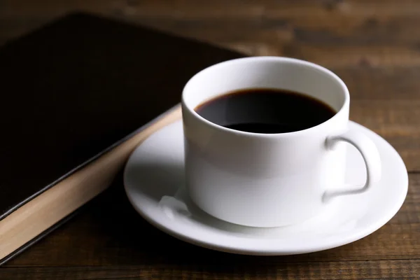 Taza de café caliente con libro sobre fondo de madera —  Fotos de Stock