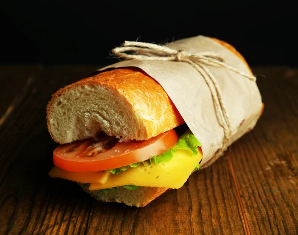 Fresh and tasty sandwich on wooden table on black background — Stock Photo, Image