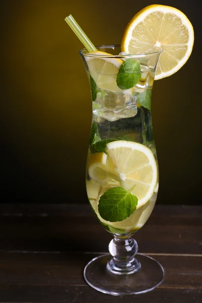 Glas cocktail med citron och mynta på bordet på mörk gul bakgrund — Stockfoto