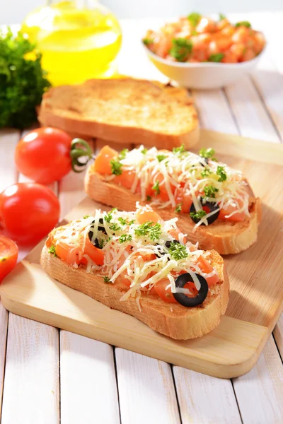 Delicioso bruschetta com tomates em corte placa close-up — Fotografia de Stock