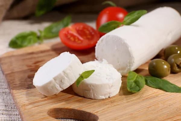 Queijo saboroso com tomate, azeitonas e manjericão, sobre tábua de corte — Fotografia de Stock