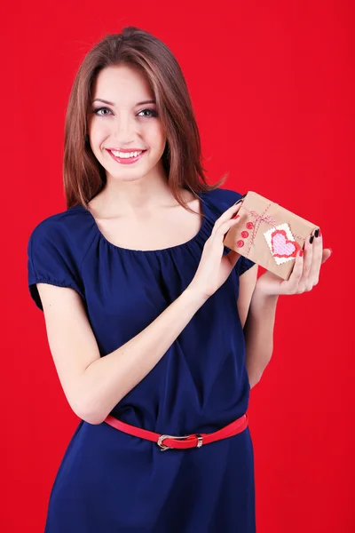 Donna attraente con scatola regalo, su sfondo colore — Foto Stock