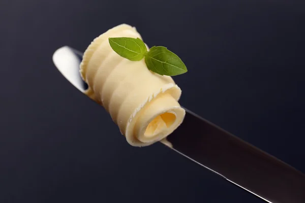 Rizo de mantequilla fresca con albahaca en el cuchillo sobre fondo gris — Foto de Stock
