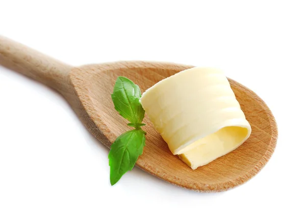 Curl of fresh butter with basil on wooden spoon, isolated on white — Stock Photo, Image