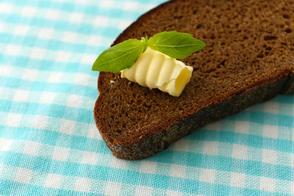 Rebanada de pan de centeno con mantequilla, sobre mantel —  Fotos de Stock