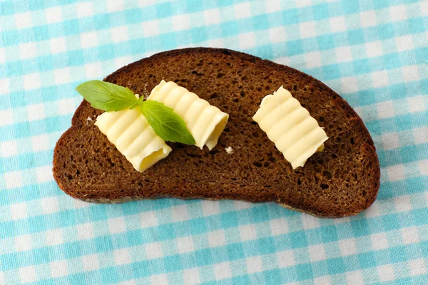 Sepotong roti gandum dengan mentega, di atas taplak meja — Stok Foto