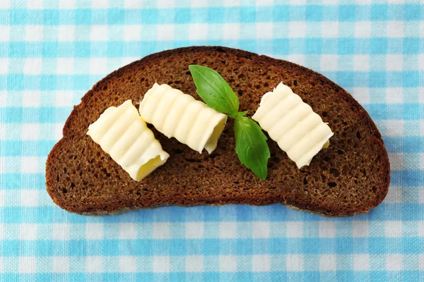 Rebanada de pan de centeno con mantequilla, sobre mantel —  Fotos de Stock