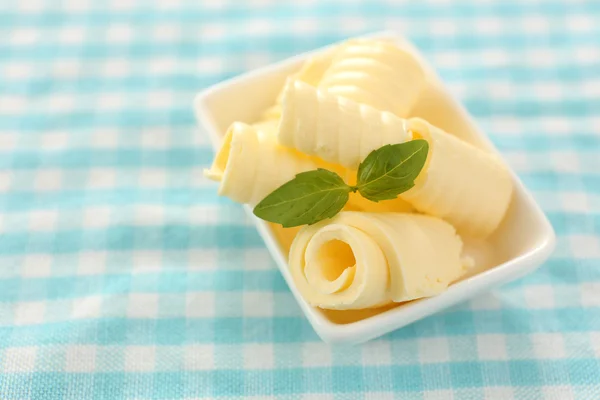 Locken frischer Butter mit Basilikum in Schüssel, auf blauer Tischdecke — Stockfoto