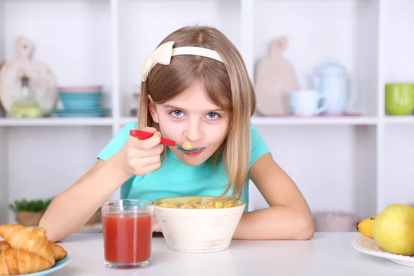 Vacker liten flicka äter frukost i köket hemma — Stockfoto