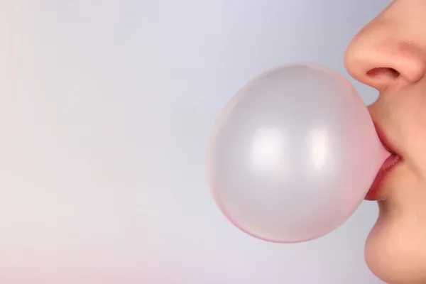 Person doing bubble with chewing gum on bright background — Stock Photo, Image