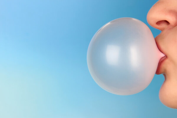 Person doing bubble with chewing gum on bright background