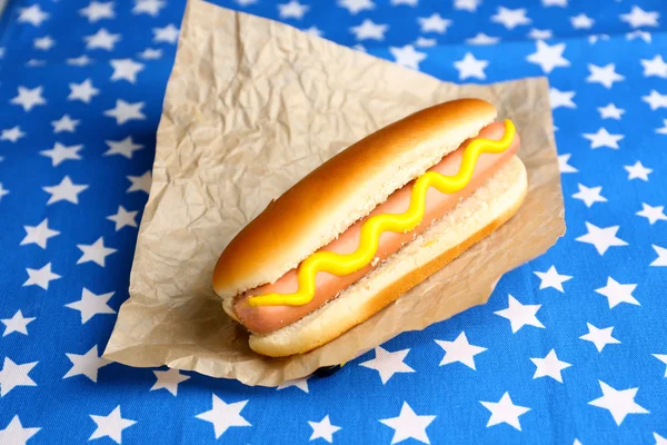 Cachorro quente saboroso em guardanapo com estrelas, isolado em branco — Fotografia de Stock