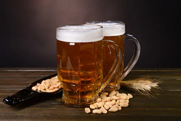 Copos de cerveja com lanche na mesa no fundo escuro — Fotografia de Stock