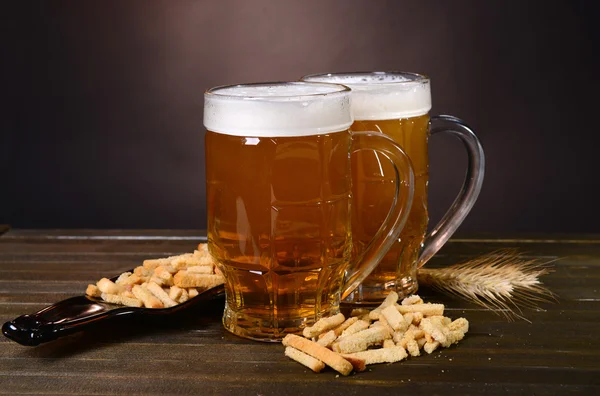 Biergläser mit Imbiss auf Tisch vor dunklem Hintergrund — Stockfoto