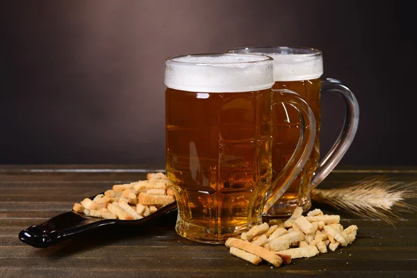 Bicchieri di birra con spuntino sul tavolo su sfondo scuro — Foto Stock