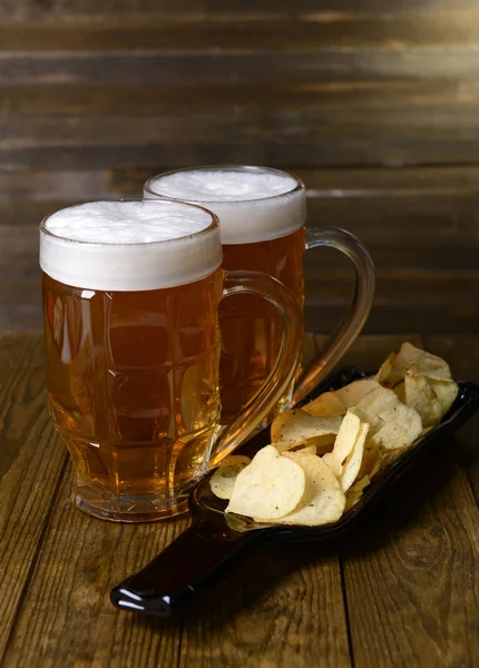 Glazen bier met snack op tafel op houten achtergrond — Stockfoto