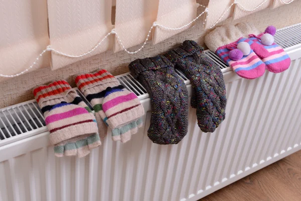 Knitted gloves drying on heating radiator — Stock Photo, Image