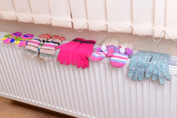 Knitted gloves drying on heating radiator — Stock Photo, Image