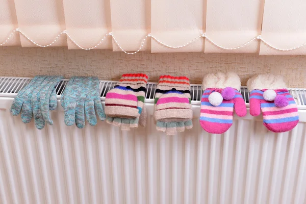 Knitted gloves drying on heating radiator — Stock Photo, Image