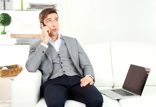 Giovane uomo d'affari che utilizza il computer portatile sul divano a casa — Foto Stock