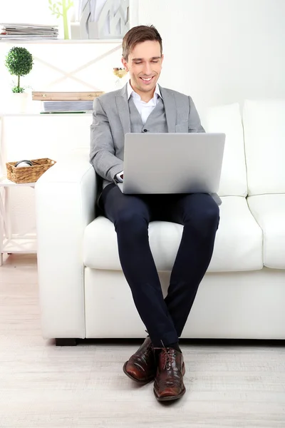 Jonge zakenman met behulp van laptop op de Bank thuis — Stockfoto