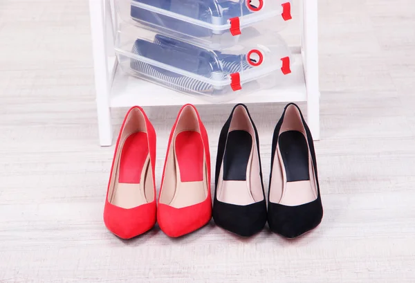 Zapatos en cajas de plástico y zapatos femeninos en el piso en la habitación — Foto de Stock