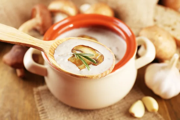 Грибной суп в деревянной ложке и горшке, на деревянном столе, на мешковине — стоковое фото