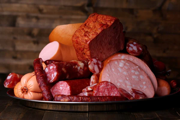 Beaucoup de différentes saucisses sur salver sur fond de bois foncé — Photo