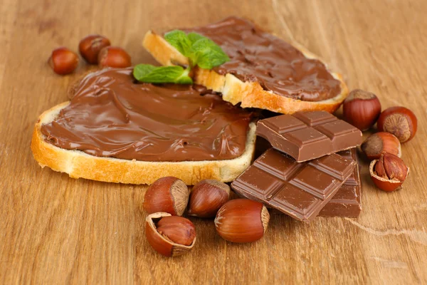 Chleb z słodka czekolada z orzechami laskowymi rozprzestrzenił się na drewniane tła — Zdjęcie stockowe
