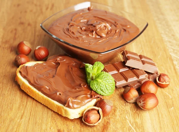 Bread with sweet chocolate hazelnut spread on wooden background — Stock Photo, Image
