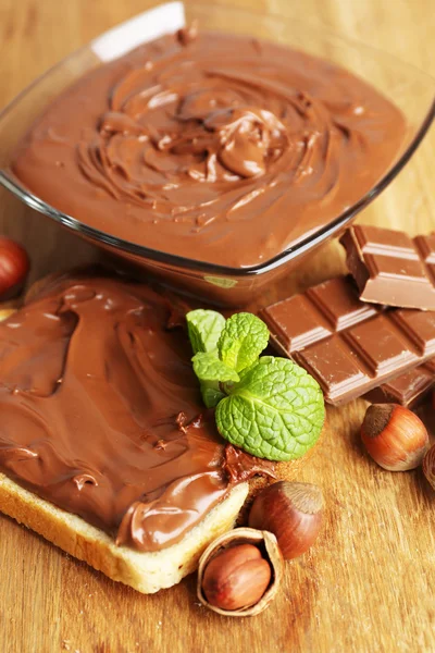 Ψωμί με γλυκιά σοκολάτα φουντούκι εξαπλωθεί σε ξύλινα φόντο — Φωτογραφία Αρχείου