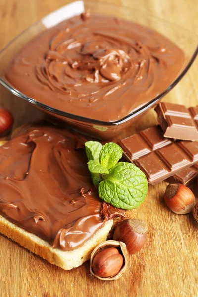 Bread with sweet chocolate hazelnut spread on wooden background — Stock Photo, Image