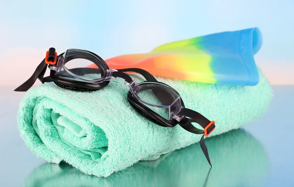 Conjunto para piscina: touca de natação, óculos e toalha sobre fundo azul — Fotografia de Stock