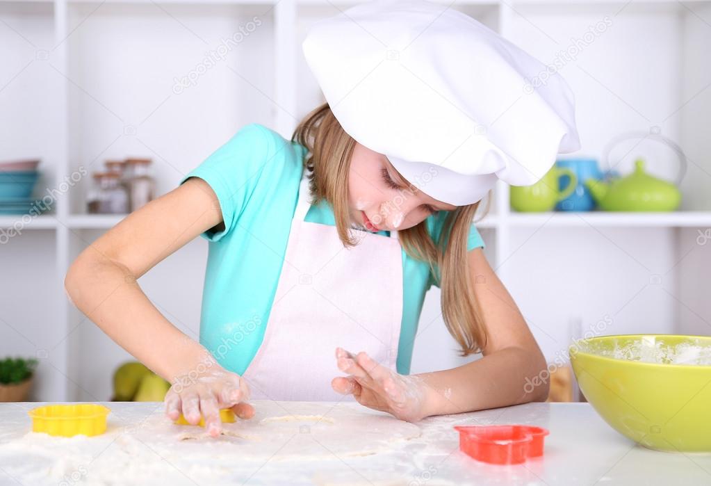 Little girl preparing cookies in kitchen at home