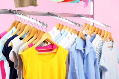 Askı, pembe bir arka plan üzerinde farklı kıyafetler