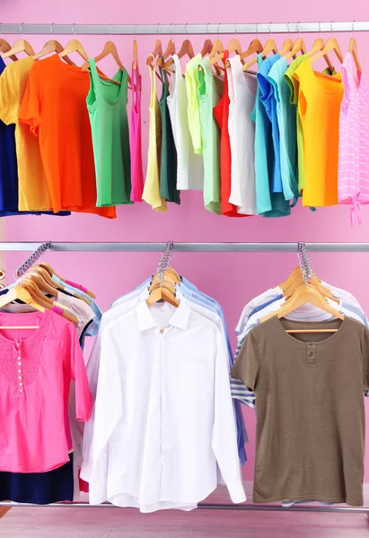 Different clothes on hangers, on pink background — Stock Photo, Image