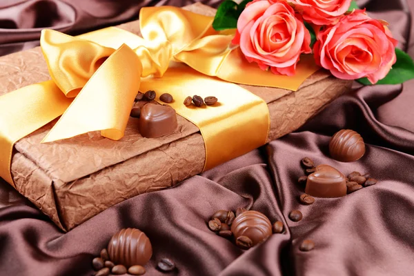 Läckra chokladpraliner i låda med blommor på brun bakgrund — Stockfoto