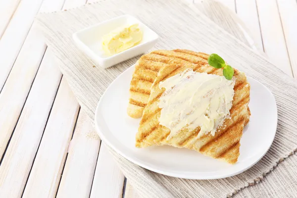 Grilled bread with butter on wooden table — Stock Photo, Image