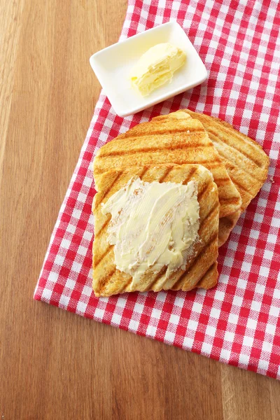 Gegrild brood met boter op houten tafel — Stockfoto