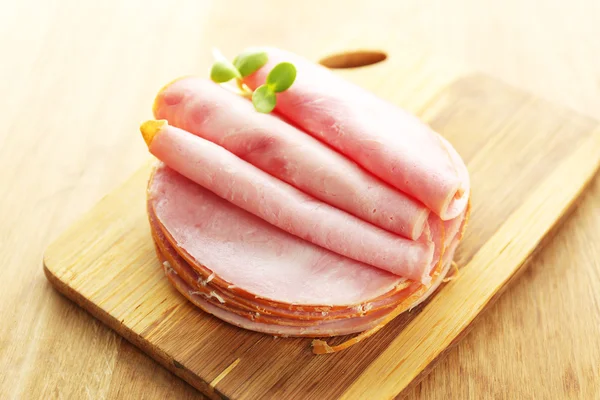 Smakelijke ham met zonnebloem spruiten op houten achtergrond — Stockfoto