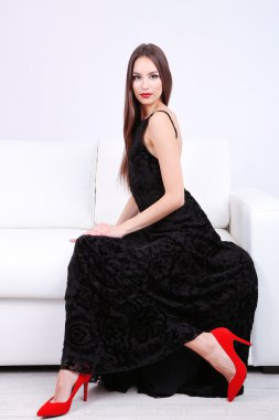 Divan beyaz zemin üzerine siyah elbiseli güzel genç kadın