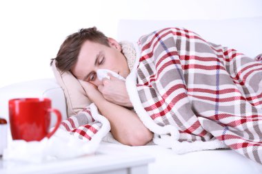 kanepe üzerinde kareli yatıyor sarılı adam hasta