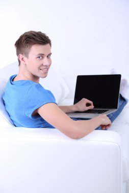 beyaz zemin üzerinde laptop ile kanepede oturan adamı