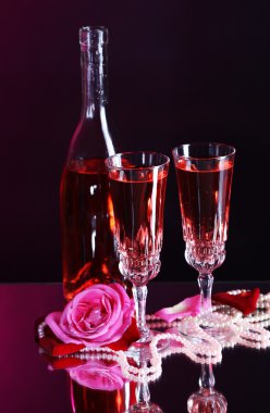 Pembe şarap gözlük, şişe ve koyu renk arka plan üzerinde gül ile kompozisyon