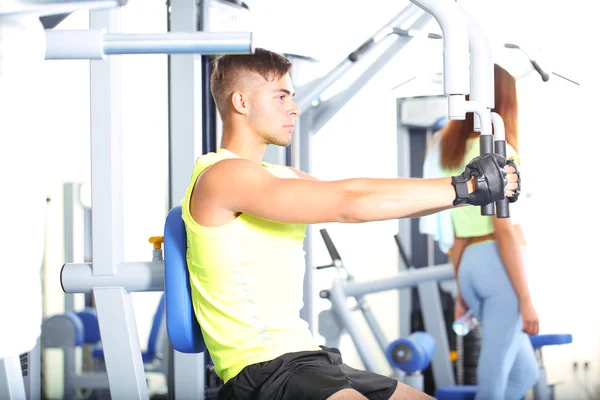 Chico y chica involucrados en simulador en el gimnasio —  Fotos de Stock