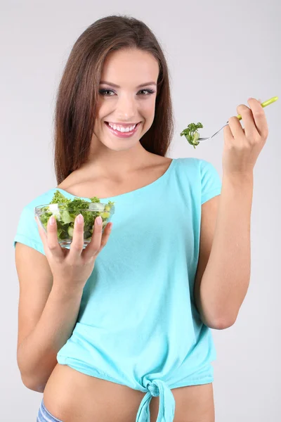 Menina bonita com salada fresca no fundo cinza — Fotografia de Stock