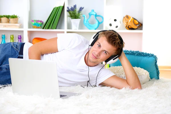 Jeune homme relaxant sur tapis avec ordinateur portable — Photo
