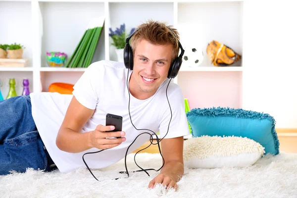Hombre joven relajándose en la alfombra y escuchando música — Foto de Stock